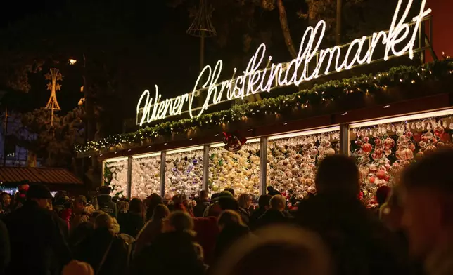 People look at Christmas baubles at the Wiener Chritkindlmarkt in front of Vienna's city hall, one of Vienna's most popular Christmas markets, in Vienna, Austria, Saturday, Nov. 16, 2024. (AP Photo/Christian Bruna)