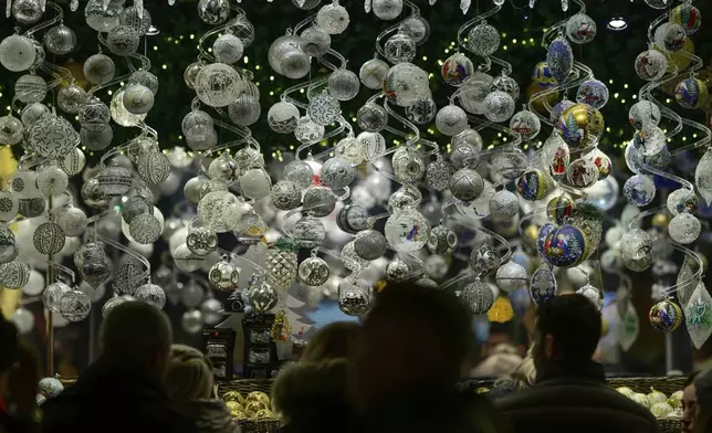 People look at Christmas baubles at the Wiener Chritkindlmarkt in front of Vienna's city hall, one of Vienna's most popular Christmas markets, in Vienna, Austria, Saturday, Nov. 16, 2024. (AP Photo/Christian Bruna)