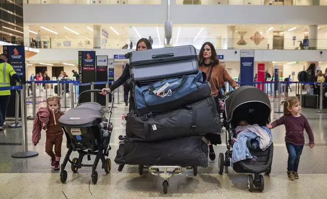 Passengers carry their luggage to check-in at the Tom Bradley International Terminal (Terminal B) at Los Angeles International Airport in Los Angeles, Wednesday, Nov. 27, 2024. (AP Photo/Damian Dovarganes)