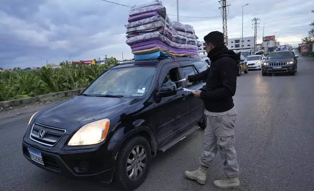 A Civil Defense worker distributes safety fliers to people returning back to their villages after the ceasefire between Hezbollah and Israel began early morning, in Tyre, south Lebanon, Wednesday, Nov. 27, 2024. (AP Photo/Hussein Malla)