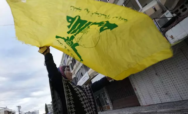 A woman waves a Hezbollah flag as she celebrates a ceasefire between Hezbollah and Israel which began early morning, in Tyre, south Lebanon, Wednesday, Nov. 27, 2024. (AP Photo/Hussein Malla)