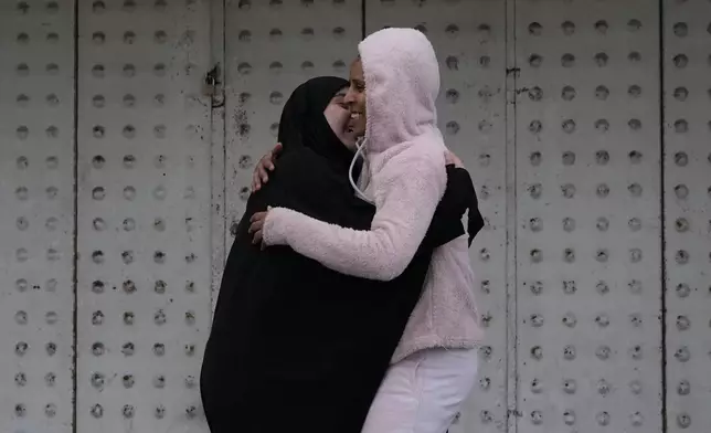 People hug each other upon their arrival at their building after the ceasefire between Hezbollah and Israel began early morning, in Tyre, south Lebanon, Wednesday, Nov. 27, 2024. (AP Photo/Hussein Malla)