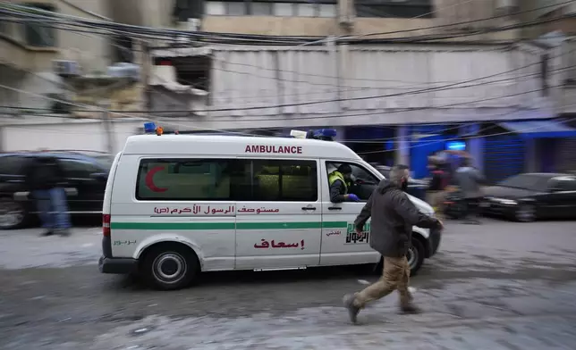 A man runs next to an ambulance arriving at the site of an Israeli airstrike that targeted a building in Beirut, Lebanon, Tuesday, Nov. 26, 2024. (AP Photo/Hassan Ammar)