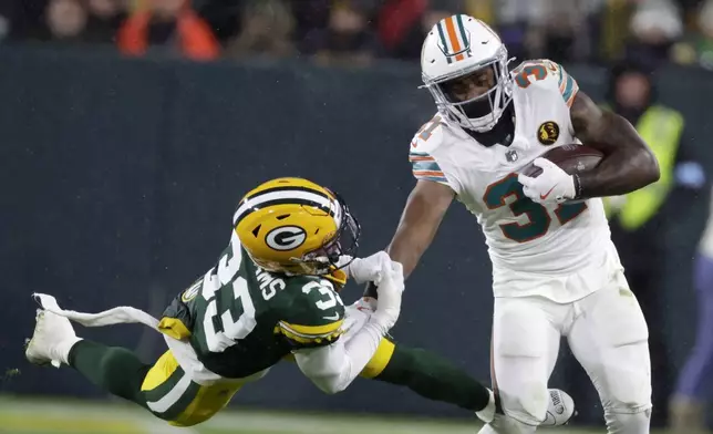 Miami Dolphins running back Raheem Mostert (31) tries to break a tackle by Green Bay Packers safety Evan Williams (33) during the second half of an NFL football game Thursday, Nov. 28, 2024, in Green Bay, Wis. (AP Photo/Matt Ludtke)