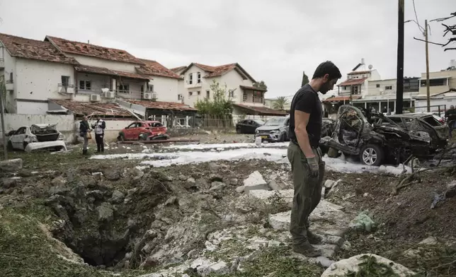 Israeli police bomb squad inspect the site after a missile fired from Lebanon hit the area in Petah Tikva, outskirts of Tel Aviv, Israel, Sunday Nov. 24, 2024. (AP Photo/Oded Balilty)