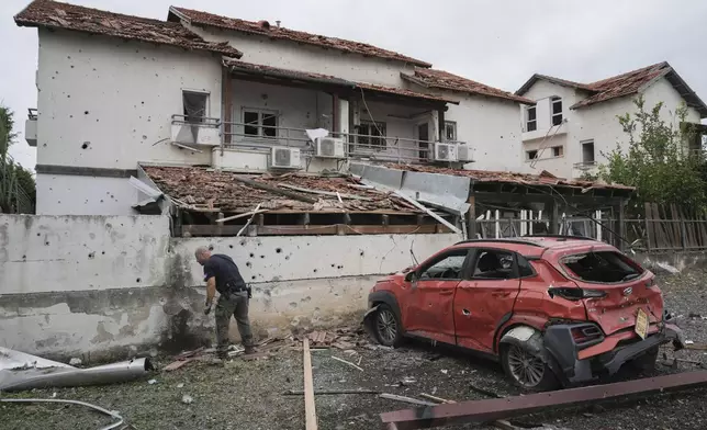 Israeli police bomb squad inspect the site after a missile fired from Lebanon hit the area in Petah Tikva, outskirts of Tel Aviv, Israel, Sunday Nov. 24, 2024. (AP Photo/Oded Balilty)