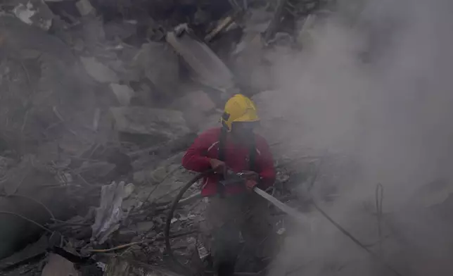 A firefighter extinguishes a fire at the site of an Israeli airstrike that hit central Beirut, Lebanon, Saturday, Nov. 23, 2024. (AP Photo/Hussein Malla)