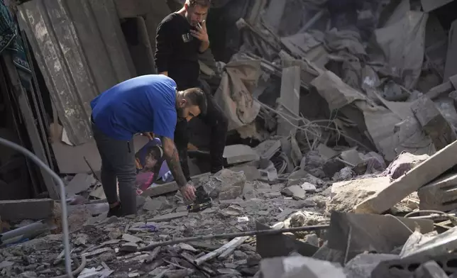 Two men stand at the site of an Israeli airstrike that hit central Beirut, Lebanon, Saturday, Nov. 23, 2024. (AP Photo/Hussein Malla)