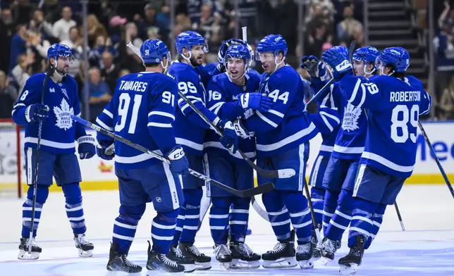 Toronto Maple Leafs right wing Mitch Marner (16), center, celebrates with teammates after scoring in overtime to defeat the Edmonton Oilers in an NHL hockey game, Saturday, Nov. 16, 2024 in Toronto. (Christopher Katsarov/The Canadian Press via AP)