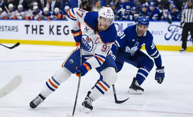 Edmonton Oilers center Connor McDavid (97) attacks the net while defended by Toronto Maple Leafs center John Tavares (91) during the first period of an NHL hockey game, Saturday, Nov. 16, 2024 in Toronto. (Christopher Katsarov/The Canadian Press via AP)