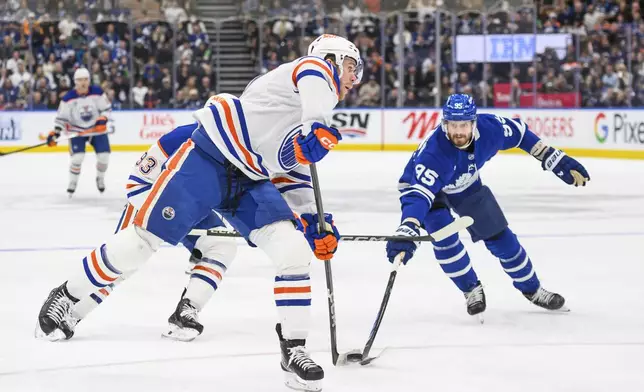 Edmonton Oilers center Connor McDavid (97) shoots on net while defended by Toronto Maple Leafs defenseman Oliver Ekman-Larsson (95) during the first period of an NHL hockey game, Saturday, Nov. 16, 2024 in Toronto. (Christopher Katsarov/The Canadian Press via AP)