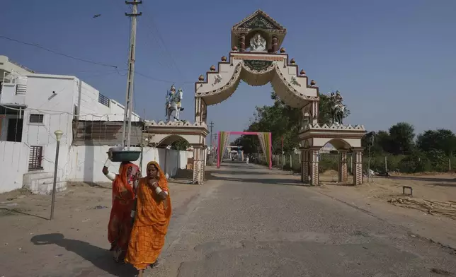 Women walks past an entrance gate of Dingucha village in Gandhinagar, India, Tuesday, Nov. 12, 2024. (AP Photo/Ajit Solanki)