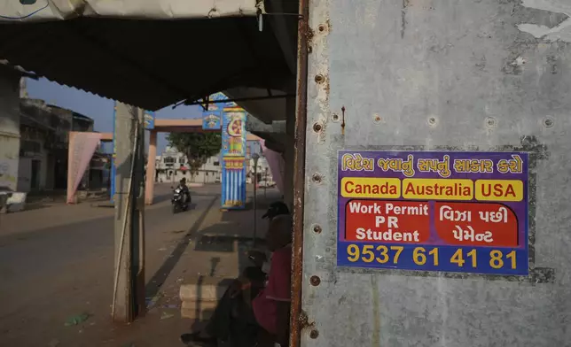 An advertising poster pasted on a shop at Dingucha village in Gandhinagar, India, Tuesday, Nov. 12, 2024. Poster reads in Gujarati "Make your dream of going abroad come true", on top and "Payment after visa". (AP Photo/Ajit Solanki)