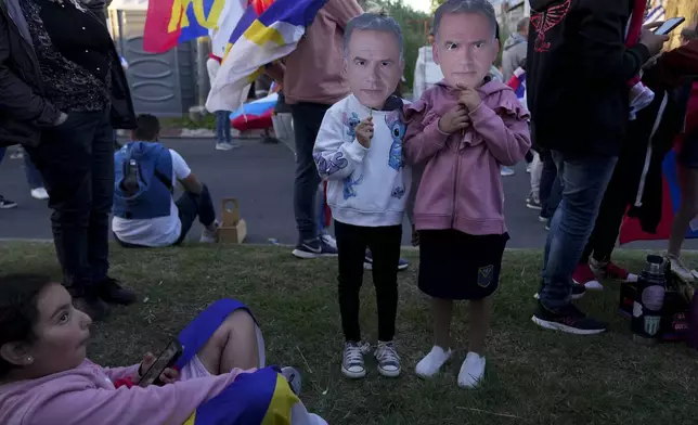 Children hold up masks of Frente Amplio presidential candidate Yamandu Orsi as they wait for the start of his closing rally ahead of the presidential run-off election in Las Piedras, Uruguay, Wednesday, Nov. 20, 2024. (AP Photo/Matilde Campodonico)