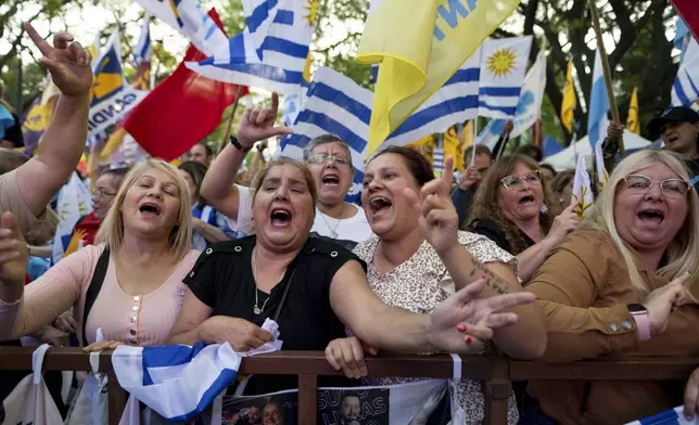 Supporters of Alvaro Delgado, presidential candidate for the ruling National Party, attend his closing rally ahead of the presidential run-off election in Montevideo, Uruguay, Wednesday, Nov. 20, 2024. (AP Photo/Santiago Mazzarovich)