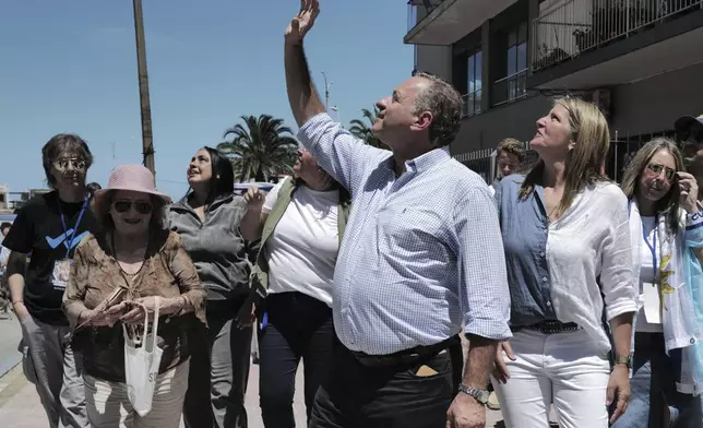Alvaro Delgado, candidate for the ruling National Party, waves to supporters after voting accompanied by his wife Leticia Lateulade, right, in the presidential run-off election in Montevideo, Uruguay, Sunday, Nov. 24, 2024. (AP Photo/Jon Orbach)