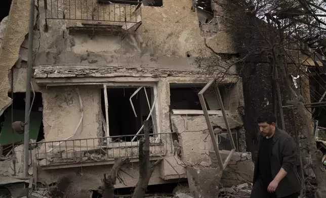 A man walks past a damaged building after a rocket fired from Lebanon hit an area in Rinatya, outskirts of Tel Aviv, Israel, Sunday, Nov. 24, 2024. (AP Photo/Leo Correa)