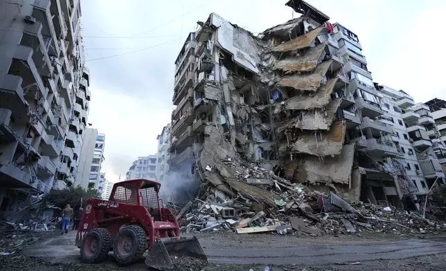 A Civil Defense worker uses a skid loader to remove the rubble in front of a destroyed building that was hit Sunday night in an Israeli airstrike in Dahiyeh, in the southern suburb of Beirut, Lebanon, Monday, Nov. 25, 2024. (AP Photo/Hussein Malla)