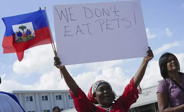 FILE - Wilda Brooks of West Palm Beach, Fla., holds up a sign reading "We don't eat pets," during a rally by members of South Florida's Haitian-American community to condemn hate speech and misinformation about Haitian immigrants, Sunday, Sept. 22, 2024, in North Miami, Fla. (AP Photo/Rebecca Blackwell, File)