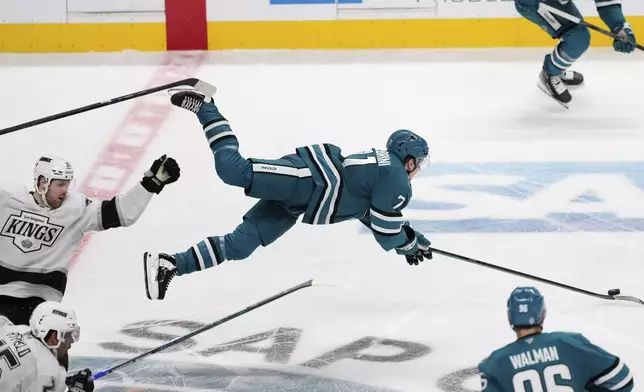 Los Angeles Kings left wing Warren Foegele, left, trips San Jose Sharks center Macklin Celebrini, center, during the third period of an NHL hockey game Monday, Nov. 25, 2024, in San Jose, Calif. (AP Photo/Godofredo A. Vásquez)