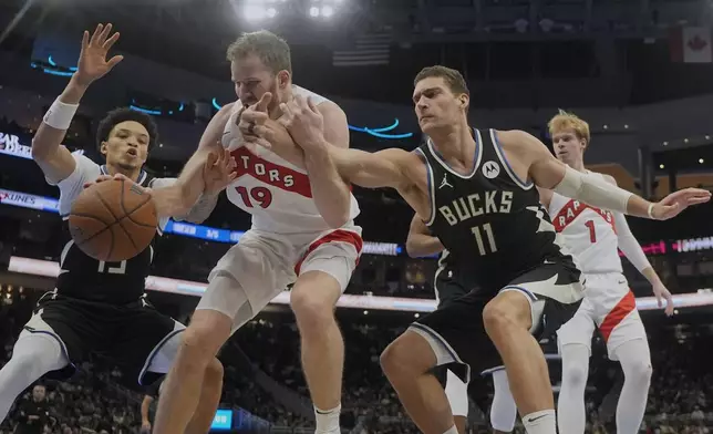 Toronto Raptors' Jakob Poeltl goes after a loose ball with Milwaukee Bucks' Brook Lopez and Ryan Rollins during the second half of an Emirates NBA Cup tournament basketball game Tuesday, Nov. 12, 2024, in Milwaukee. (AP Photo/Morry Gash)