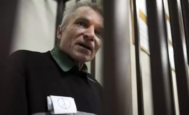 Imprisoned Kremlin critic Alexei Gorinov, stands in a cage at the court as his second trial for criticizing Russia's actions in Ukraine swiftly nears its conclusion in Vladimir, Russia, Friday, Nov. 29, 2024. (AP Photo/Dmitry Serebryakov)