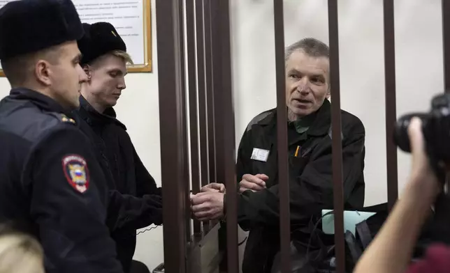 Imprisoned Kremlin critic Alexei Gorinov, 63, right, appears in court as his second trial for criticizing Russia's actions in Ukraine swiftly nears its conclusion stands in a cage in Vladimir, Russia, Friday, Nov. 29, 2024. (AP Photo/Dmitry Serebryakov)