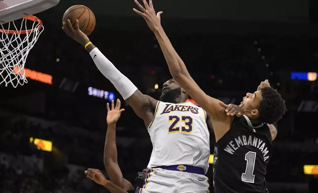 Los Angeles Lakers' LeBron James (23) goes to the basket against San Antonio Spurs' Victor Wembanyama during the first half of an Emirates NBA Cup basketball game, Friday, Nov. 15, 2024, in San Antonio. (AP Photo/Darren Abate)