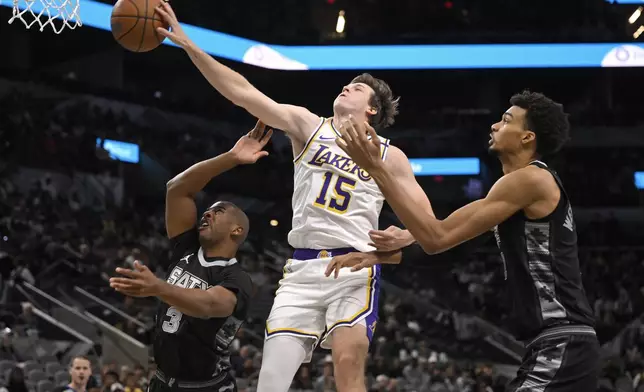 Los Angeles Lakers' Austin Reaves (15) tangles with San Antonio Spurs' Victor Wembanyama, right, and Chris Paul during the first half of an Emirates NBA Cup basketball game, Friday, Nov. 15, 2024, in San Antonio. (AP Photo/Darren Abate)