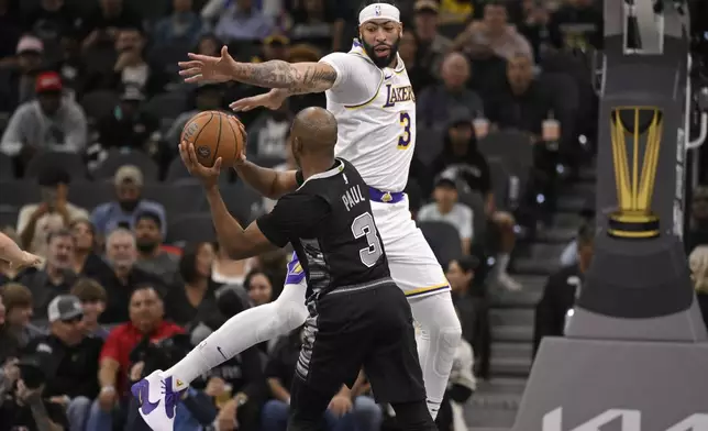 San Antonio Spurs' Chris Paul, front, looks to pass as he is defended by Los Angeles Lakers' Anthony Davis during the first half of an Emirates NBA Cup basketball game, Friday, Nov. 15, 2024, in San Antonio. (AP Photo/Darren Abate)