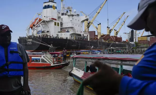 People wait at the Stabroek Market to ferry across the Demerara River, where a cargo ship is docked at the port in Georgetown, Guyana, Tuesday, Nov. 19, 2024. (AP Photo/Matias Delacroix)