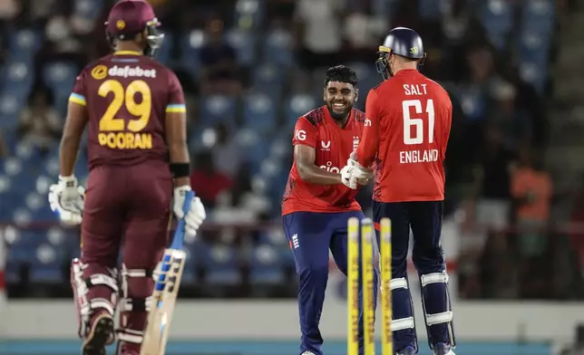 England's Rehan Ahmed celebrates with wicket keeper Phil Salt the dismissal of West Indies' Nicholas Pooran during the fourth T20 cricket match at Daren Sammy National Cricket Stadium in Gros Islet, St. Lucia, Saturday, Nov. 16, 2024. (AP Photo/Ricardo Mazalan)