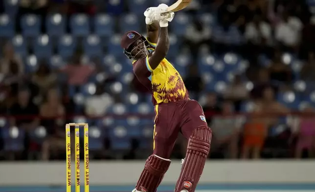 West Indies' captain Rovman Powell eyes the ball after hitting for six runs against England during the fourth T20 cricket match at Daren Sammy National Cricket Stadium in Gros Islet, St. Lucia, Saturday, Nov. 16, 2024. (AP Photo/Ricardo Mazalan)