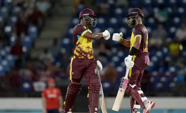 West Indies' Shai Hope, right, and Evin Lewis celebrate scoring a hundred runs during their partnership against England at the fourth T20 cricket match at Daren Sammy National Cricket Stadium in Gros Islet, St. Lucia, Saturday, Nov. 16, 2024. (AP Photo/Ricardo Mazalan)