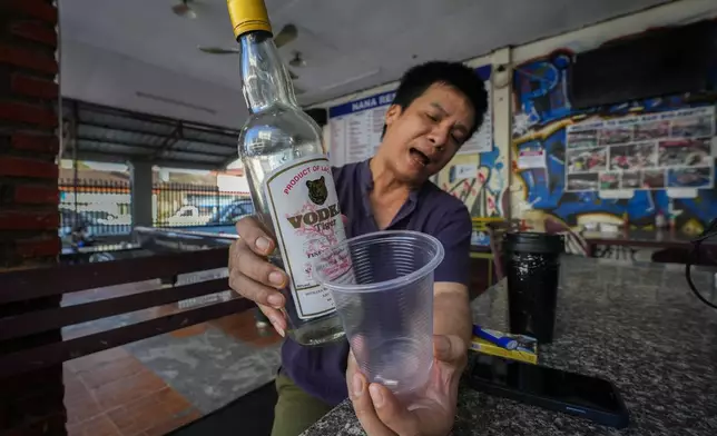 Duong Duc Toan, the manager of Nana Backpack hostel displays a bottle of vodka, in the bar of the hostel in Vang Vieng, Laos, Tuesday, Nov. 19, 2024. (AP Photo/Anupam Nath)