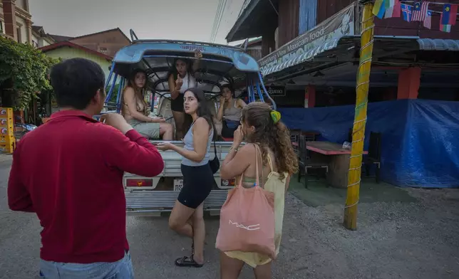 Tourists talk to a bar owner in Vang Vieng, Laos, Tuesday, Nov. 19, 2024. (AP Photo/Anupam Nath)