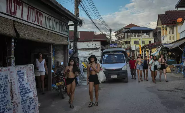 Foreign tourists walk in a street near bars in Vang Vieng, Laos, Tuesday, Nov. 19, 2024. (AP Photo/Anupam Nath)