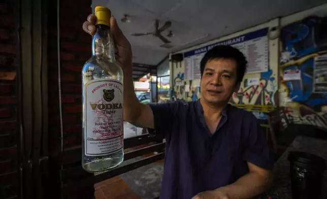 Duong Duc Toan, the manager of Nana Backpack hostel displays a bottle of vodka, in the bar of the hostel in Vang Vieng, Laos, Tuesday, Nov. 19, 2024. (AP Photo/Anupam Nath)