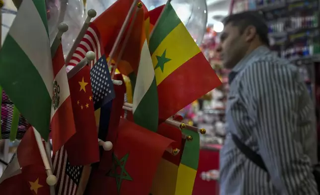 A foreigner walks by flags on display at a stationery store at the Yiwu wholesale market in Yiwu, east China's Zhejiang province on Nov. 8, 2024. (AP Photo/Andy Wong)