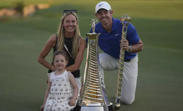 Rory McIlroy of Northern Ireland poses with his wife, Erica Stoll and Daughter, Poppy McIlroy alongside the trophies after winning the World Tour Golf Championship in Dubai, United Arab Emirates, Sunday, Nov. 17, 2024. (AP Photo/Altaf Qadri)