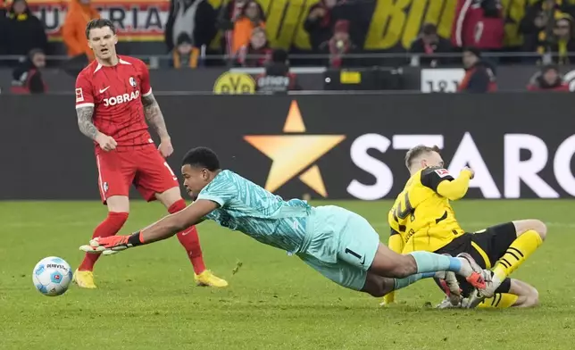 Freiburg's goalkeeper Noah Atubolu saves by Dortmund's Maximilian Beier during the German Bundesliga soccer match between Borussia Dortmund and SC Freiburg at the Signal-Iduna Park in Dortmund, Germany, Saturday, Nov. 23, 2024. (AP Photo/Martin Meissner)