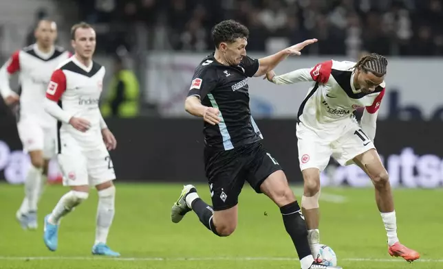 Bremen's Milos Veljkovic, left, and Frankfurt's Hugo Ekitike fight for the ball during the German Bundesliga soccer match between Eintracht Frankfurt and Werder Bremen in Frankfurt Main, Germany, Saturday, Nov. 23, 2024. (Thomas Frey/dpa via AP)