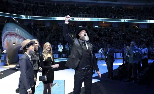 Joe Thornton, standing with his wife Tabea and children River and Ayla, waves to the crowd during a ceremony to retire his jersey before an NHL hockey game between the San Jose Sharks and the Buffalo Sabres Saturday, Nov. 23, 2024, in San Jose, California. (Ezra Shaw/Pool Photo via AP)