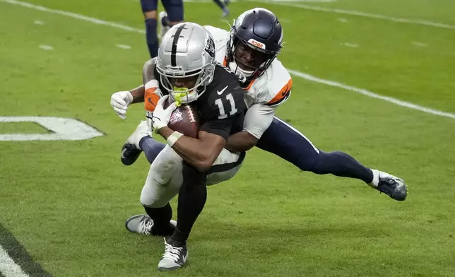 Denver Broncos cornerback Ja'Quan McMillian tackles Las Vegas Raiders wide receiver Tre Tucker (11) during the first half of an NFL football game, Sunday, Nov. 24, 2024, in Las Vegas. (AP Photo/John Locher)