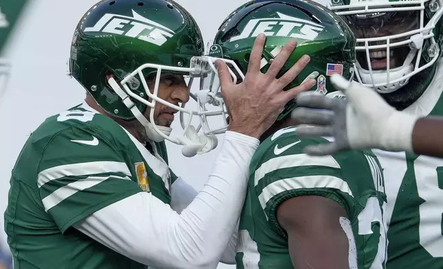 New York Jets quarterback Aaron Rodgers (8) congratulates running back Breece Hall (20) after Hall ran the ball for a touchdown against the Indianapolis Colts during the second quarter of an NFL football game, Sunday, Nov. 17, 2024, in East Rutherford, N.J. (AP Photo/Seth Wenig)