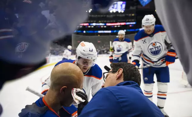 Edmonton Oilers defenseman Darnell Nurse (25) is attended to by medical personnel and teammates after colliding with Toronto Maple Leafs right wing Ryan Reaves (75) during the second period of an NHL hockey game, Saturday, Nov. 16, 2024 in Toronto. (Christopher Katsarov/The Canadian Press via AP)