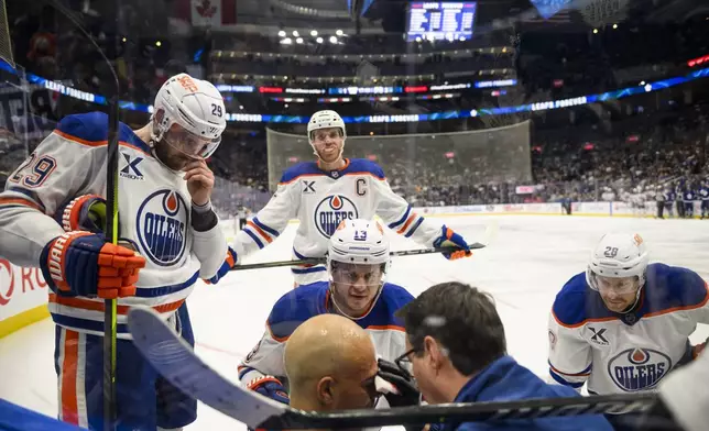 Edmonton Oilers defenseman Darnell Nurse (25) is attended to by medical personnel and teammates after colliding with Toronto Maple Leafs right wing Ryan Reaves (75) during the second period of an NHL hockey game, Saturday, Nov. 16, 2024 in Toronto. (Christopher Katsarov/The Canadian Press via AP)