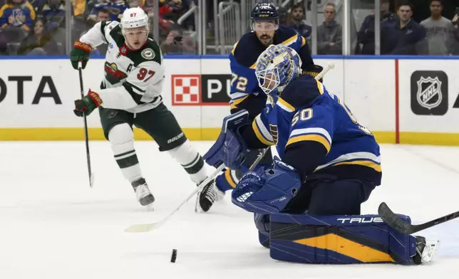 Minnesota Wild left wing Kirill Kaprizov (97) and St. Louis Blues defenseman Justin Faulk (72) look on as goaltender Jordan Binnington (50) eyes the puck during the first period of an NHL hockey game Tuesday, Nov. 19, 2024, in St. Louis. (AP Photo/Jeff Le)