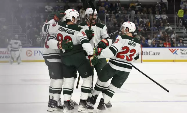 Minnesota Wild center Marco Rossi (23) celebrates with teammates after a goal scored by right wing Ryan Hartman, far left, against the St. Louis Blues during the first period of an NHL hockey game Tuesday, Nov. 19, 2024, in St. Louis. (AP Photo/Jeff Le)