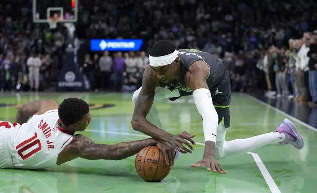 Houston Rockets forward Jabari Smith Jr. (10) and Minnesota Timberwolves forward Jaden McDaniels (3) fight for the ball during the first half of an Emirates NBA cup basketball game, Tuesday, Nov. 26, 2024, in Minneapolis. (AP Photo/Abbie Parr)